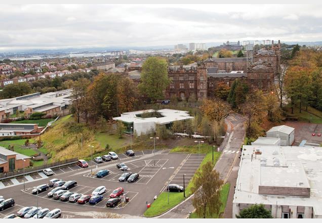 The building nestles into a sloping, wooded site beneath the gothic facade of the former Glasgow Royal Lunatic Asylum.